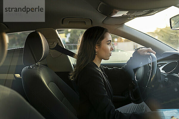 Junge Geschäftsfrau schaut beim Autofahren weg