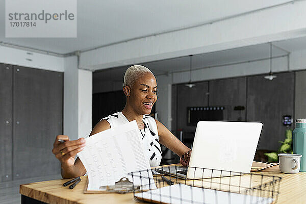 Lächelnde Geschäftsfrau  die in einem modernen Büro arbeitet und einen Laptop benutzt
