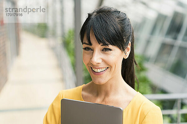Geschäftsfrau lächelnd mit Laptop im Büro
