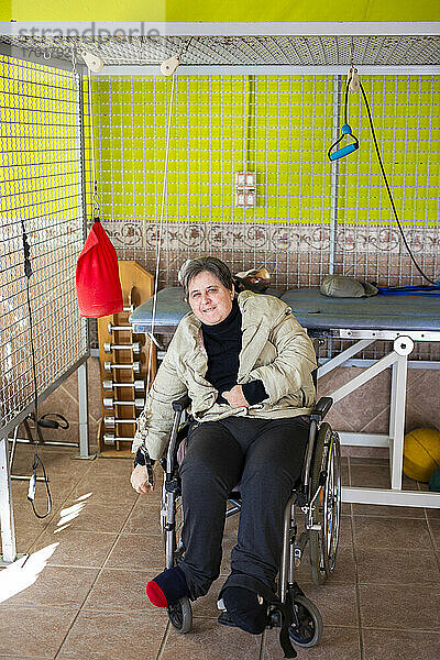 Ältere behinderte Frau  die auf einem Rollstuhl sitzt und mit einem Seil im Rehabilitationszentrum trainiert