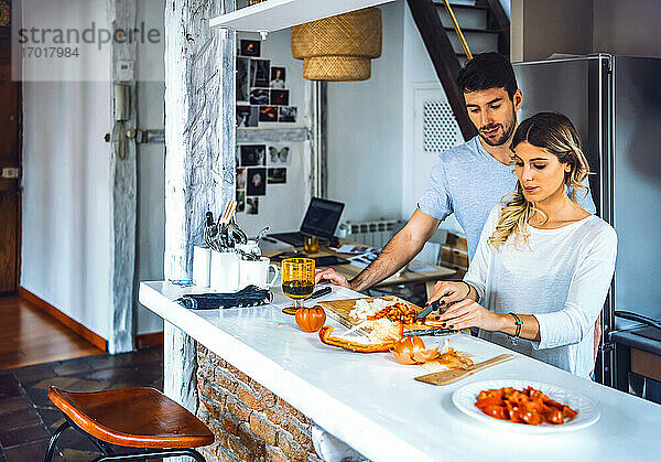 Junges Paar bei der gemeinsamen Zubereitung von Speisen in der Küche zu Hause