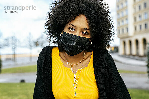 Nahaufnahme einer jungen Frau mit Afro-Haar und schwarzer Gesichtsmaske