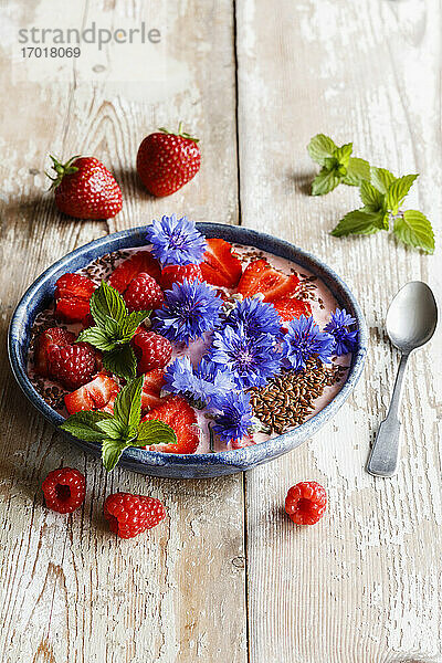 Teller mit Joghurt mit Himbeeren  Erdbeeren  Kornblumen und Minze