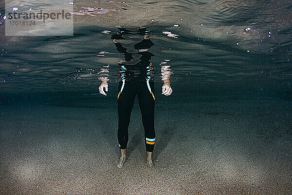 Unterwasseransicht eines niedrigen Ausschnitts eines Mannes auf sandigem Meeresboden