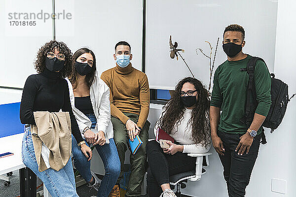 Männlicher und weiblicher Kollege mit Gesichtsschutzmaske vor weißer Wand im Büro
