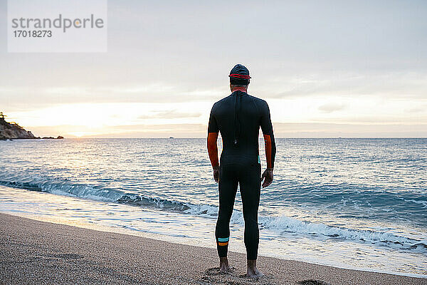 Männlicher Schwimmer bewundert das Meer bei Sonnenuntergang