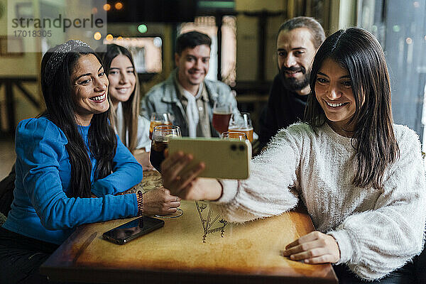 Lächelnde Freunde nehmen Selfie auf Smartphone in Bar