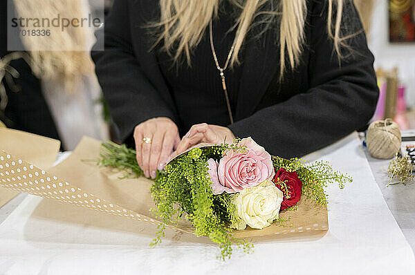 Florist wickelt Blumenstrauß mit Papier im Blumenladen ein