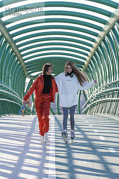 Junge Frau  die mit ihrem Freund auf einer Brücke Schlittschuh läuft