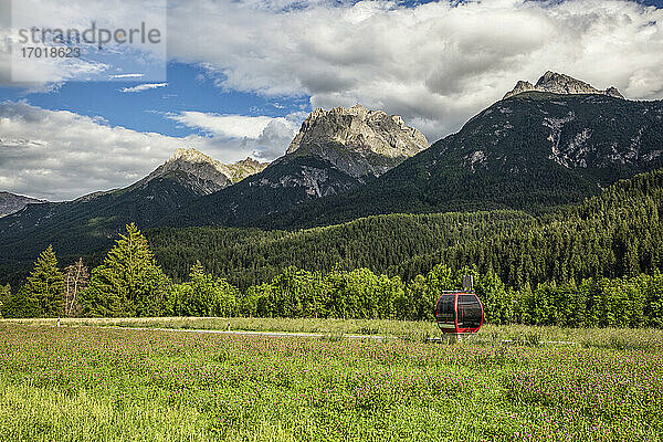 Blick auf ein grünes  bewaldetes Engadin-Tal mit Luftseilbahn im Vordergrund