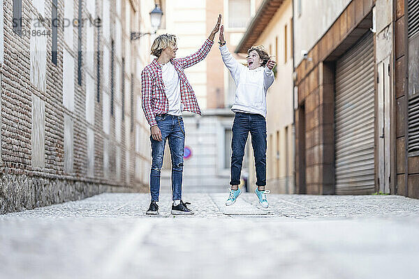 Junger Mann gibt aufgeregtem Jungen auf dem Fußweg ein High-Five