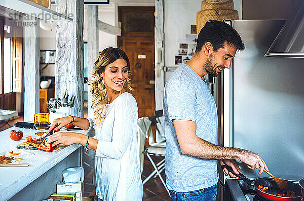 Glückliches junges Paar bei der gemeinsamen Zubereitung von Speisen in der Küche zu Hause