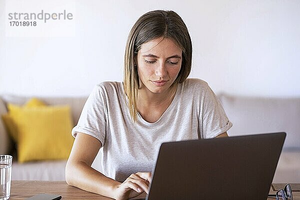 Schöne Frau  die einen Laptop bei der Arbeit zu Hause benutzt
