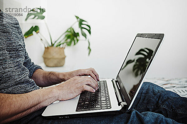 Mann arbeitet zu Hause sitzend am Laptop