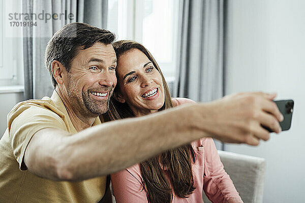 Glückliches reifes Paar spricht Selfie durch Handy zu Hause