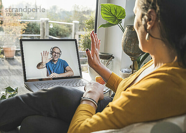 Mann und Frau winken während eines Videogesprächs auf dem Laptop