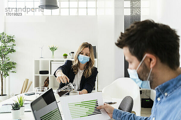 Geschäftsleute mit Schutzmasken bei der Arbeit im Büro