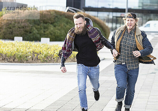 Schwule Freunde halten sich beim Laufen auf der Straße in der Stadt an den Händen