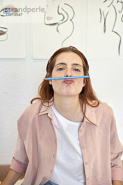 Künstlerin mit Bleistift über dem Mund bei sich zu Hause