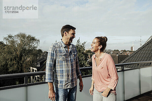 Fröhliches reifes Paar  das lachend auf dem Balkon steht