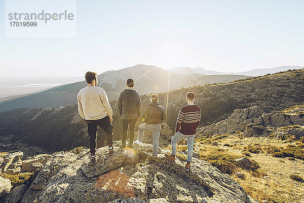 Freunde betrachten die Aussicht  während sie an einem sonnigen Tag auf einem Berg stehen