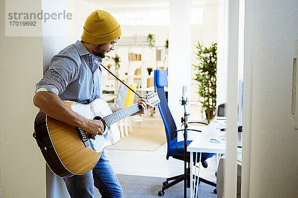Musiker spielt Gitarre  während er im Studio steht