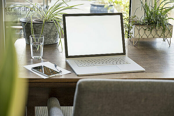 Weißes Gerät Bildschirm von Laptop durch Glas auf dem Tisch zu Hause