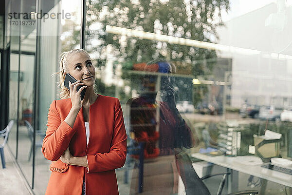 Weibliche Unternehmerin spricht mit einem Smartphone vor einem Bürogebäude