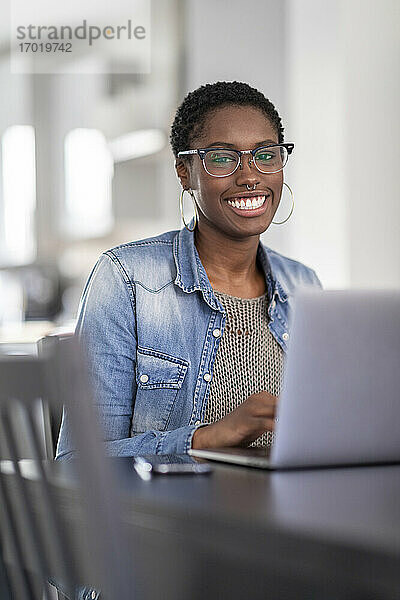 Lächelnde Frau arbeitet zu Hause am Laptop