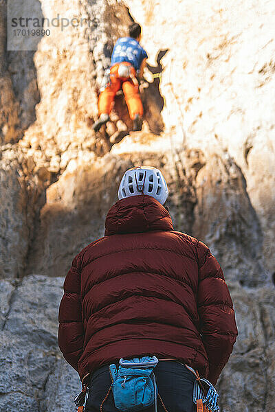 Männliche Athleten besteigen einen felsigen Berg an einem sonnigen Tag