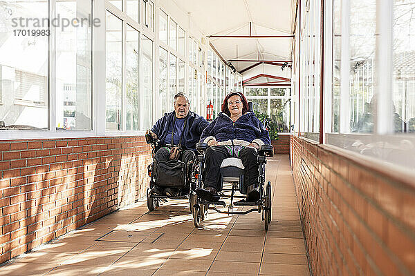 Behinderter Mann und Frau im Rollstuhl im Korridor