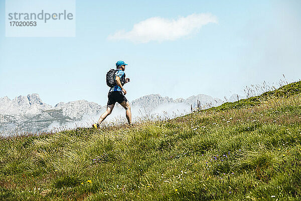 Älterer Sportler beim Trailrunning in den Bergen auf einer Wiese