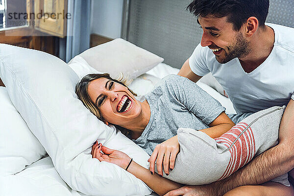 Lachendes junges Paar  das zu Hause im Bett liegt