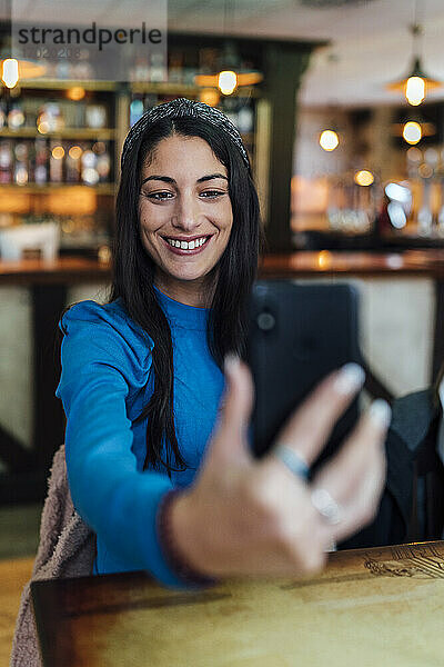 Attraktive Frau nimmt Selfie auf Smartphone in Bar