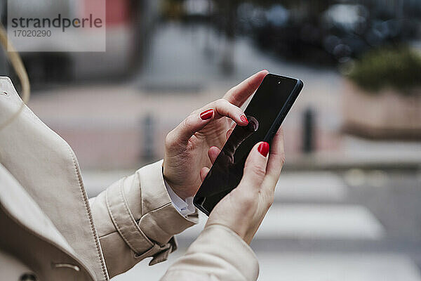 Mittlere erwachsene Frau benutzt Smartphone im Freien