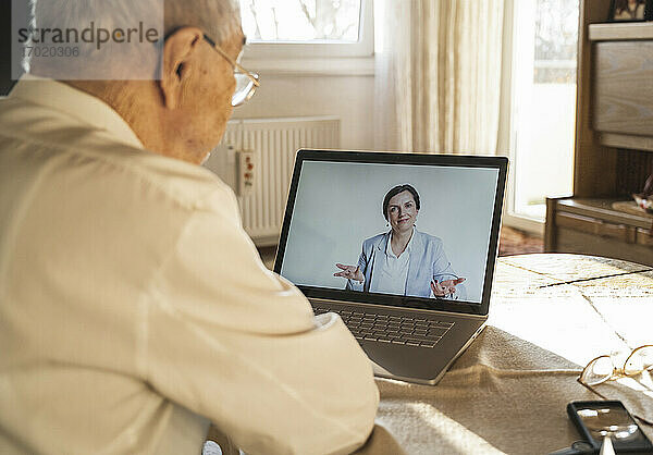 Eine Ärztin berät einen älteren männlichen Patienten während eines Videoanrufs zu Hause