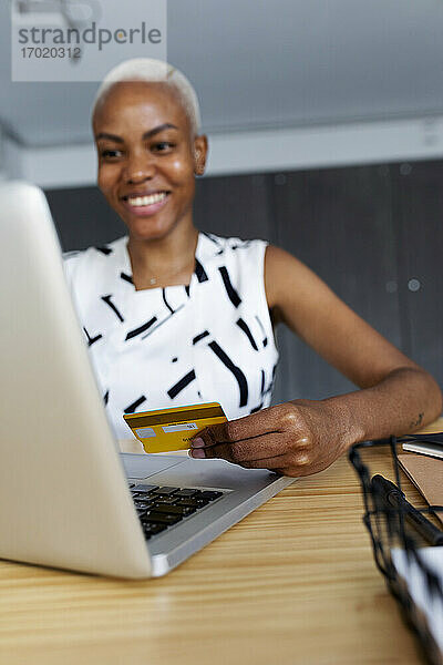 Geschäftsfrau  die im Büro sitzt und einen Laptop benutzt  um eine Online-Zahlung mit einer Kreditkarte vorzunehmen