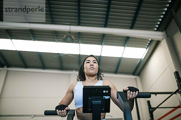 Selbstbewusste Sportlerin an einem Trainingsgerät im Fitnessstudio