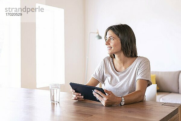Nachdenkliche Unternehmerin bei der Arbeit zu Hause mit digitalem Tablet