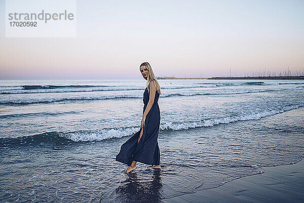 Junge Frau  die am Strand Platja de Llevant im Wasser spazieren geht