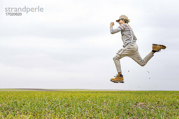 Junger Mann springt und posiert in der Luft auf einer Wiese