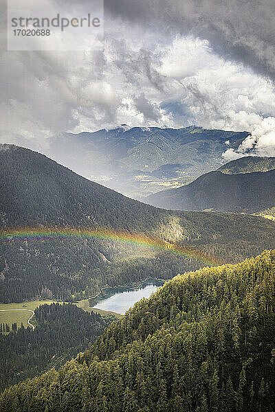 Regenbogen über Berglandschaft mit See
