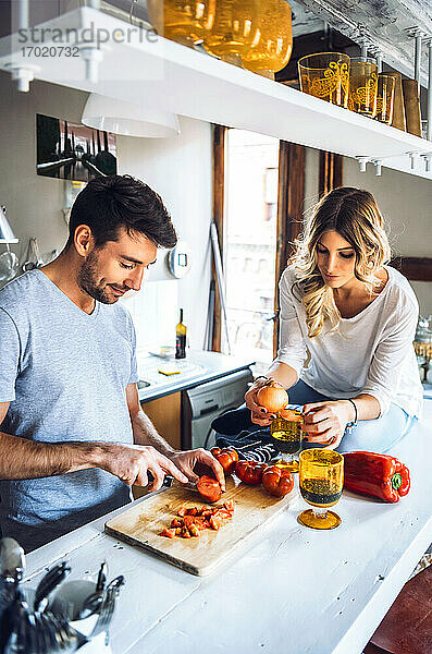 Junger Mann bereitet mit Freundin in der Küche zu Hause Essen zu