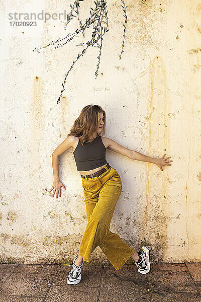 Junge Frau tanzt an der Wand im Freien