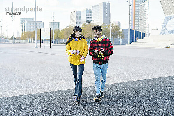Junges Paar lächelnd beim Spaziergang auf der Straße in der Stadt