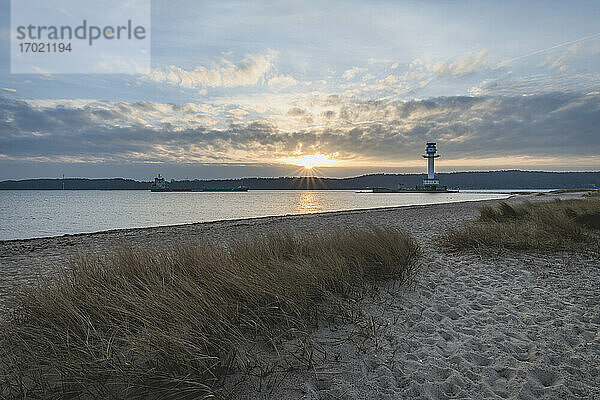 Deutschland  Schleswig-Holstein  Friedrichsort  Sandstrand bei Sonnenaufgang mit Leuchtturm im Hintergrund