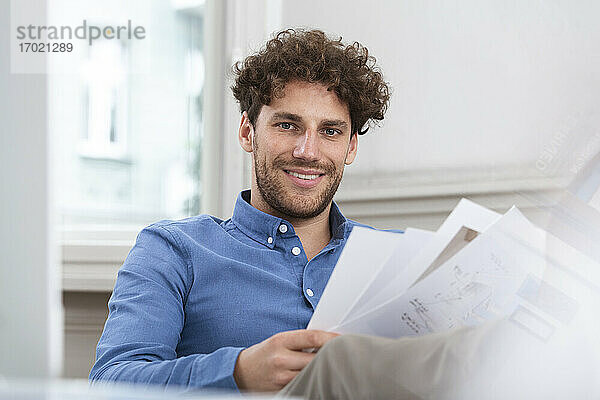 Lächelnder Geschäftsmann mit Dokument im Büro