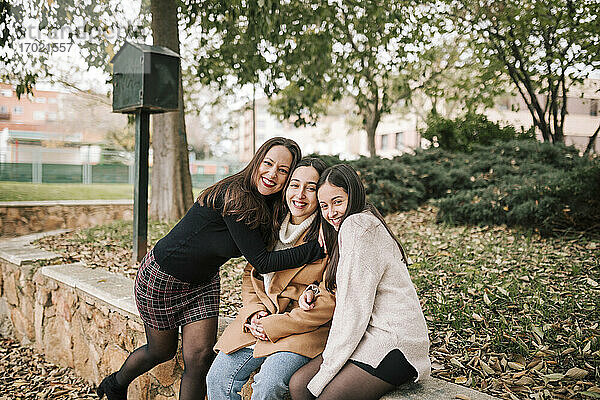 Lächelnde Mutter mit Töchtern  die das Wochenende im Park genießen