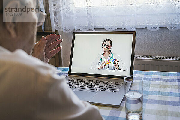 Ärztin für Allgemeinmedizin berät einen älteren Mann während eines Videoanrufs zu Hause