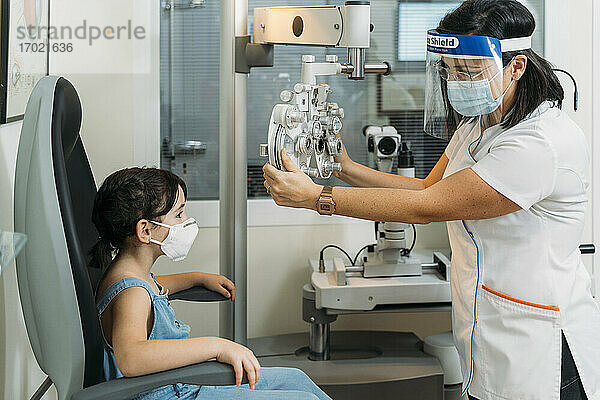 Optikerin  mittlerer Erwachsener  die einen Propther für einen medizinischen Test in der Klinik während COVID-19 einstellt